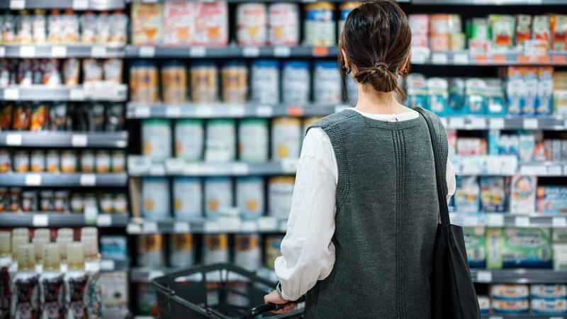 Women looking at cans on infant formula on a grocery store shelf 