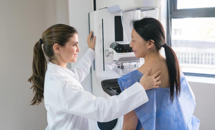 Female radiologic technologist helping patient get in position for a mammogram