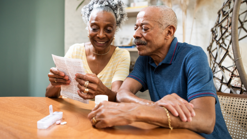senior couple at kitchen table reviewing medicine label information