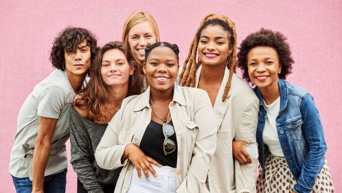 Image of diverse women posing in front of a pink wall