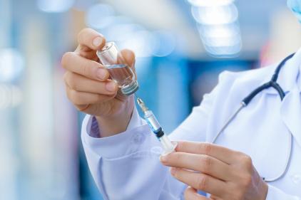 Doctor extracting contents of vial into syringe