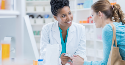Photo of female pharmacist talking to female customer at counter of pharmacy.