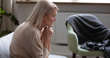 Middle-aged woman with hunched back seated on couch at home.