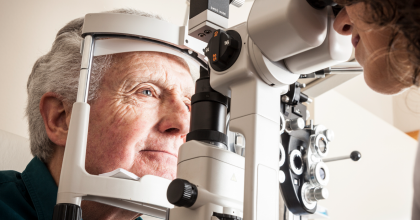 Optometrist giving eye exam to senior patient.