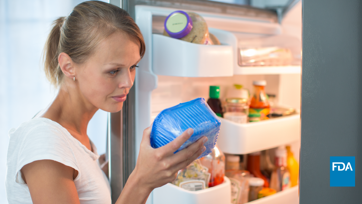 Woman looks at date label on food package removed from refrigerator