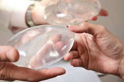 Hands holding a pair of breast implants.