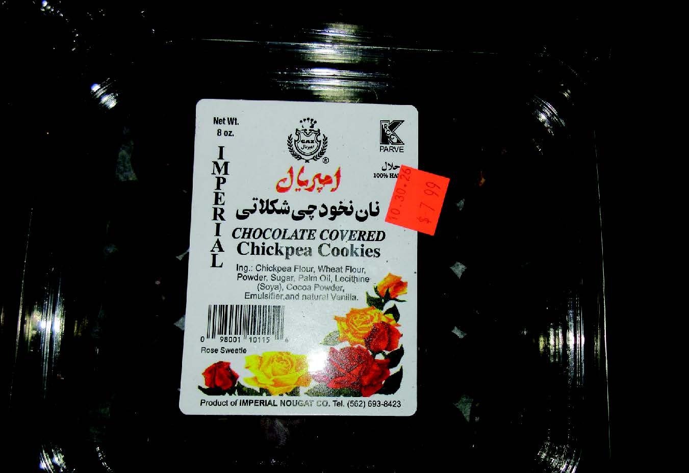 Image showing a black plastic container with a white product label affixed to the front. The label reads "IMPERIAL" vertically on the left side and displays the brand name in Persian script ("امپریال") in red. The product is identified as "CHOCOLATE COVERED Chickpea Cookies" in English and Persian. The label indicates a net weight of 8 oz. and lists ingredients: Chickpea Flour, Wheat Flour, Powder, Sugar, Palm Oil, Lecithine (Soya), Cocoa Powder, Emulsifier, and natural Vanilla. A Kosher PARVE certification