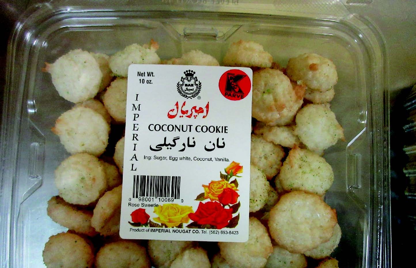 A image showing a clear plastic container filled with small, round, pale-colored coconut cookies. A white product label is affixed to the front of the container. The label reads "IMPERIAL" vertically on the left and displays the brand name in Persian script ("امپریال") in red. The product is identified as "COCONUT COOKIE" in English and "نان نارگیلی" in Persian. Net weight is listed as 10 oz. Ingredients listed are: Sugar, Egg white, Coconut, Vanilla. A red Kosher PARVE certification logo appears in the upp