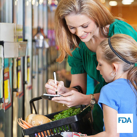 Mother and daughter look at shopping list while shopping in grocery store