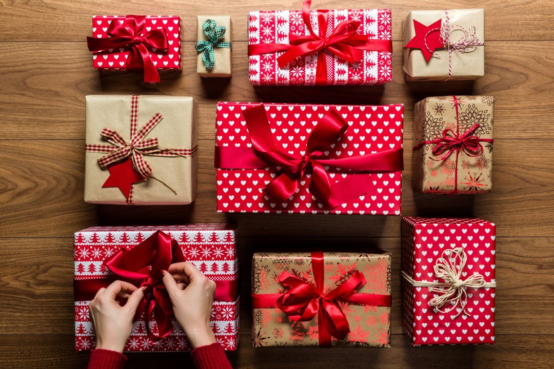 Three rows of presents, one present bow being tied by hands