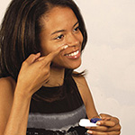 African American woman holding a contact lens up to her eye