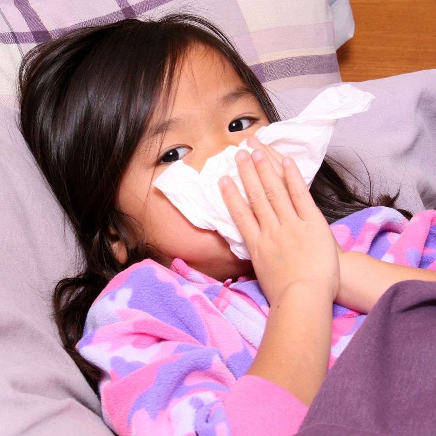 Niño sonándose la nariz, enfermo en la cama con un resfriado.