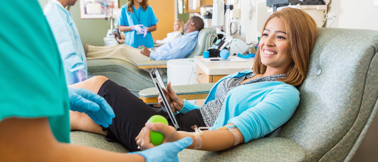Smiling young asian woman donating blood in clinic.