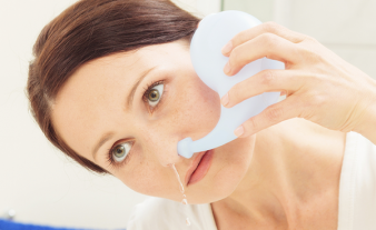 Una mujer enjuagar los cavidades nasales con tetera neti