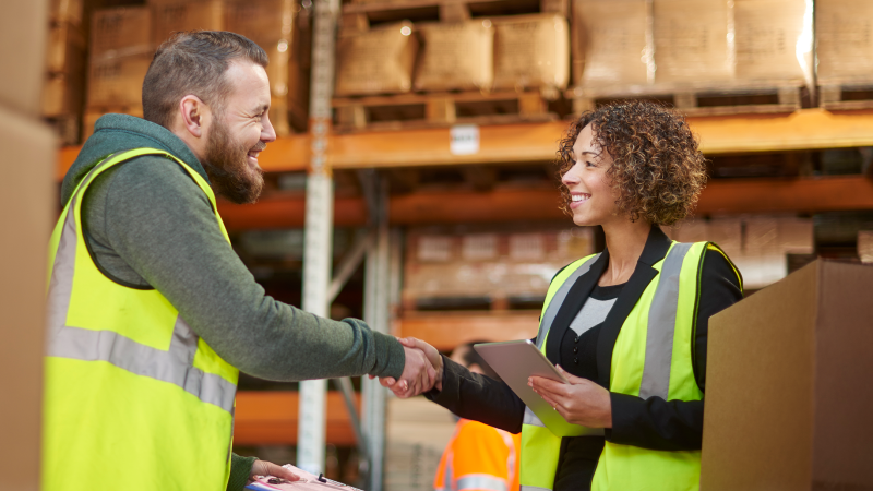 Employees shaking hands in a warehouse and an employee using a pallet jack