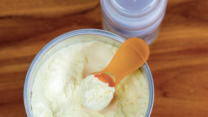 Open can of infant formula with a scoop