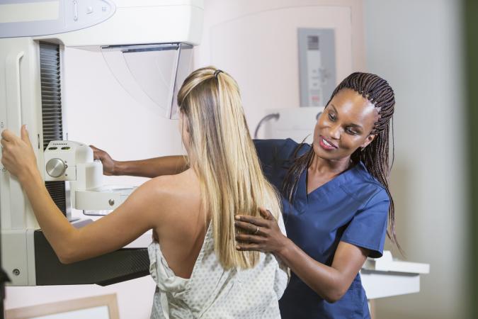 Woman being positioned for a mammogram by a healthcare technician 