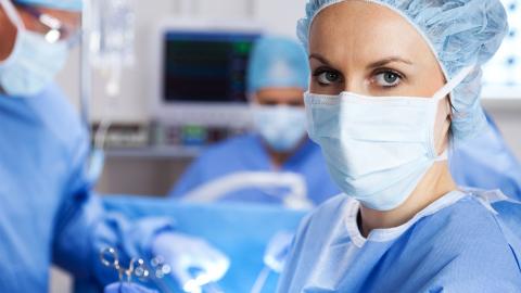 Health care staff wearing PPE: masks, gloves, gowns, head coverings.