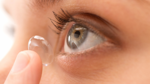 Primer plano de una persona poniéndose una lente de contacto en el ojo.