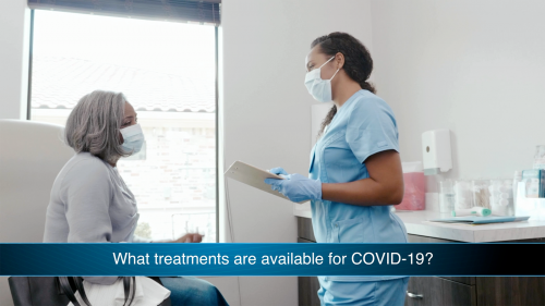 Older female patient speaking with doctor about COVID-19 treatment in hospital room.