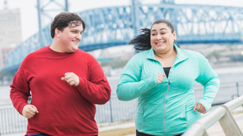 Two adults jogging and smiling at each other.