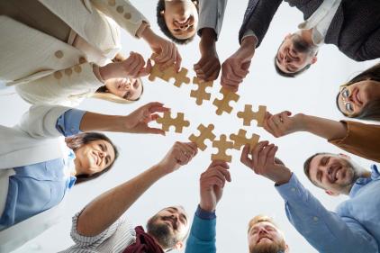 Professional team connecting jigsaw pieces in a huddle