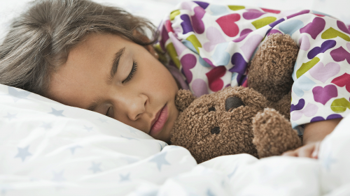 Image of child sleeping with teddy bear, representing the long-term effects some individuals may experience after COVID-19 infection