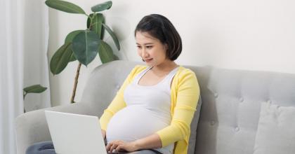 Image of pregnant Asian woman working on a laptop
