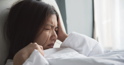 Woman laying in bed with her hand on her head