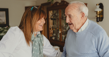 Image of older man and his female caretaker facing each other. 