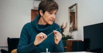 Woman at home with nasal swab studying instructions for a COVID-19 test