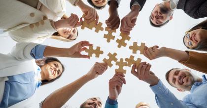 Professional team connecting jigsaw pieces in a huddle