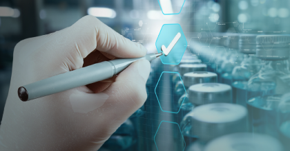A conceptual image depicting quality control: a hand in a white glove uses a stylus to place a checkmark in a hexagonal box on a futuristic digital interface. The background shows blurred rows of medical vials in a laboratory or manufacturing setting.