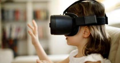 A girl sits down with her hands up and wears a virtual reality headset. 