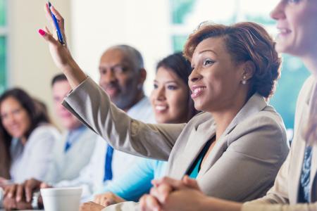 African American Businesswoman Raising Hand Asking Question In Business Conference