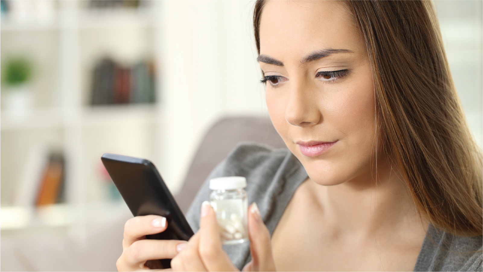 Woman holding a phone and a bottle of medication