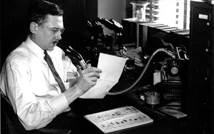 James Munch holding a sheet of paper and the microphone of a large recording device